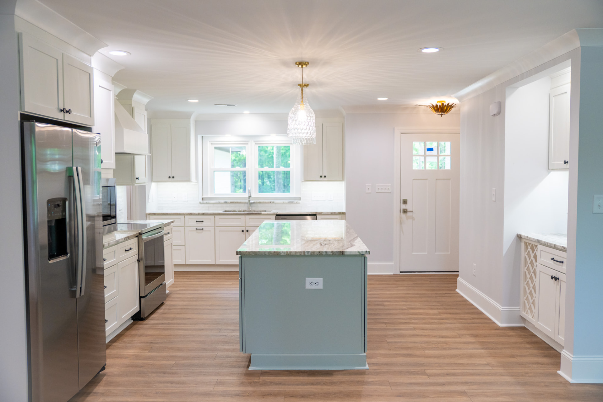 Woodland Kitchen Renovation — Reconfigured kitchen with painted cabinetry, quartzite counters and a sage island opening to the rear entry.
