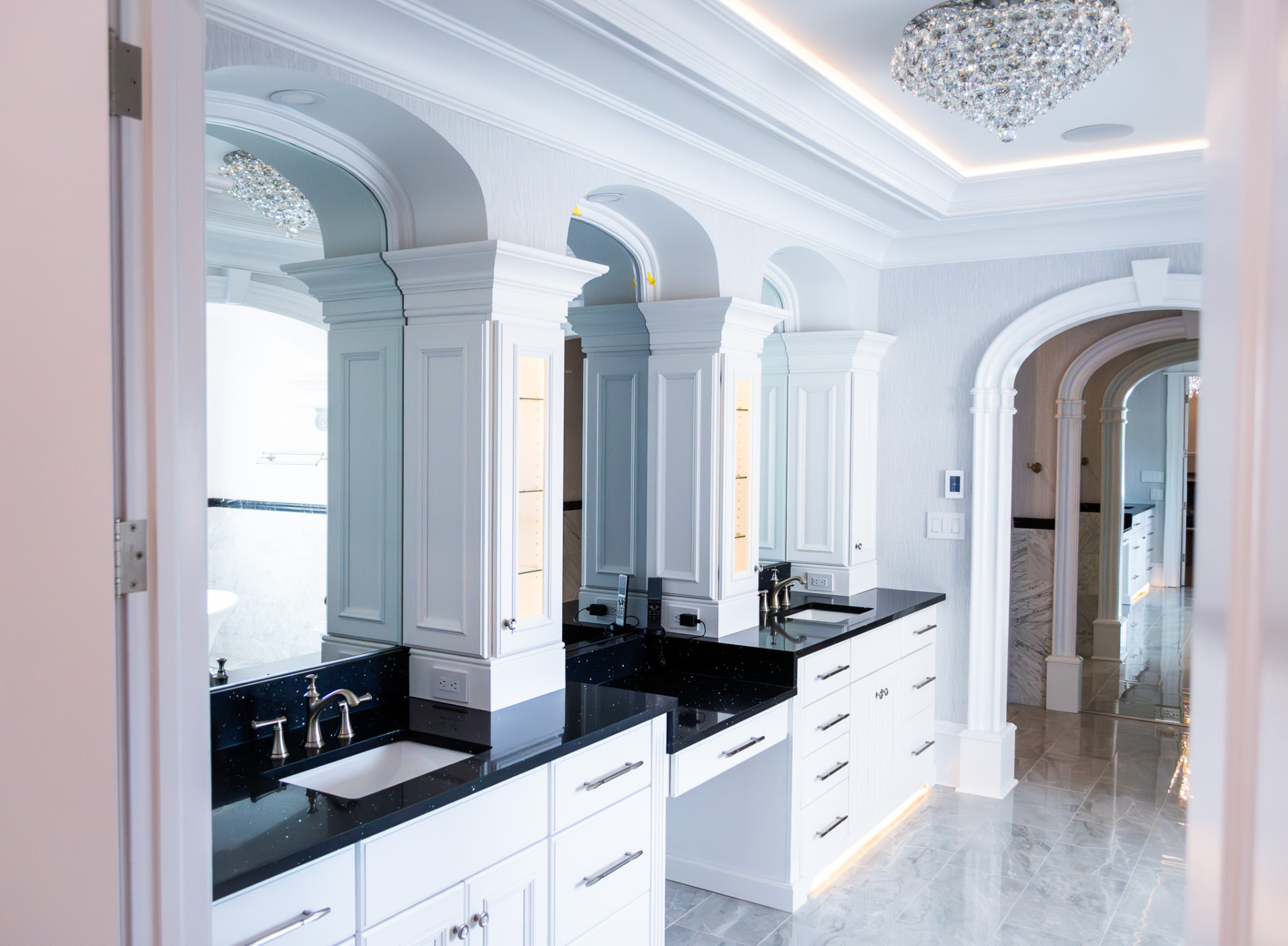 Primary Bath — Arched Vanities — Twin vanities beneath arched mirror niches, quartz counters, integrated lighting and a coved ceiling detail.